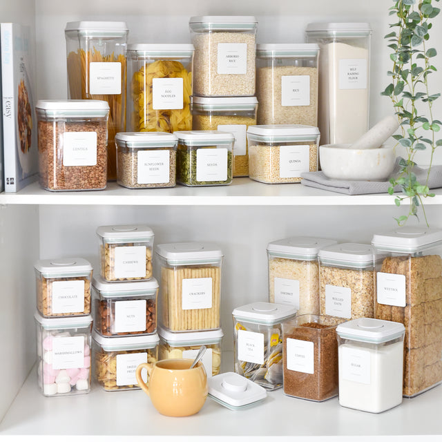 Labelled push-top pantry containers lined up on a pantry shelf