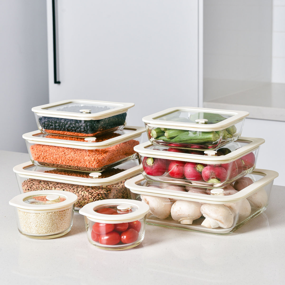 Cream glass food storage containers with glass lids holding fresh produce and prepped meals