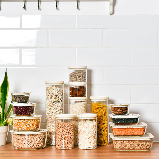 Graduated glass pantry jars filled with dry goods on a timber bench